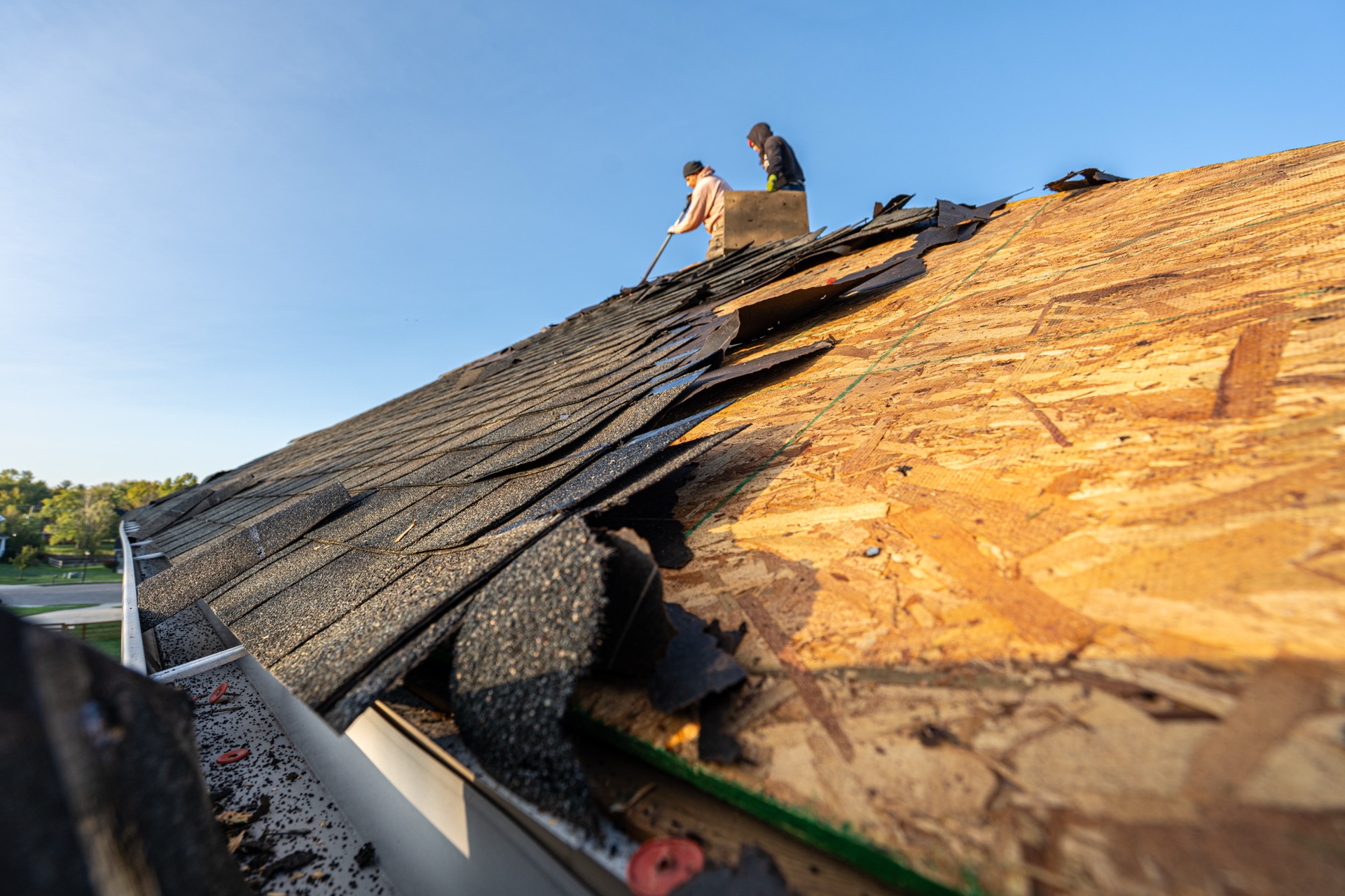 Liberty Township Roofing crew tearing off shingles at golden hour