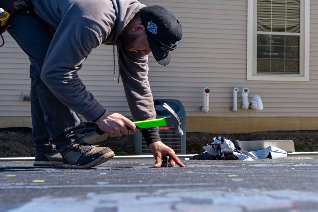 Liberty Township Roofing technician hand-nailing a shingle