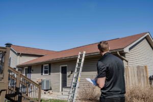 roof inspector looking upon a roof with a orange asphalt shingled roof with a ladder setup