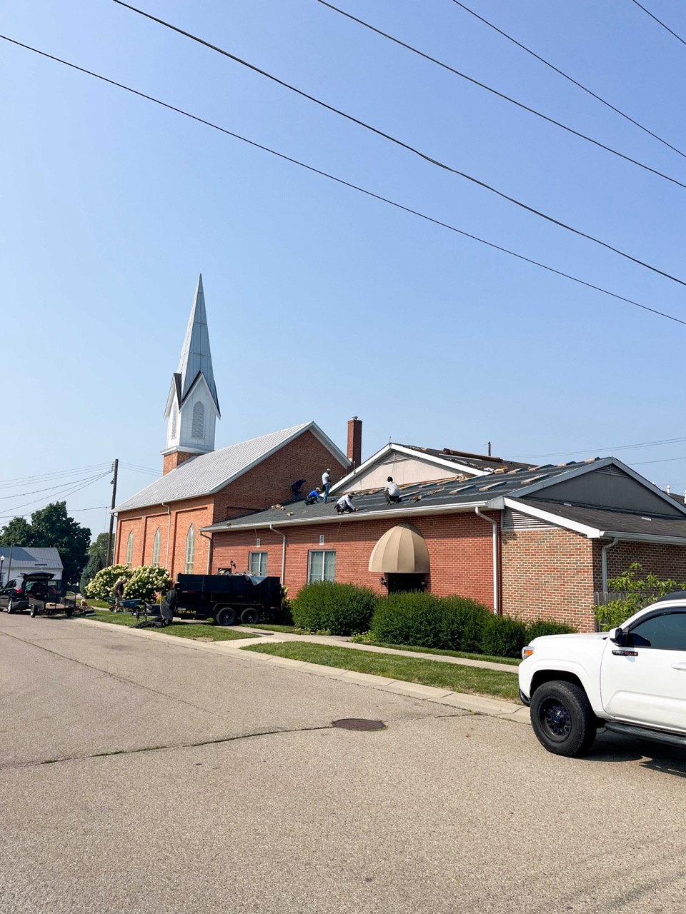 a brick single story church with a shingled roof.