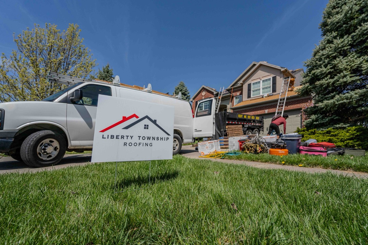 liberty township roofing yard sign in the foreground as a roofing installation crew works on a two story residential home in the background